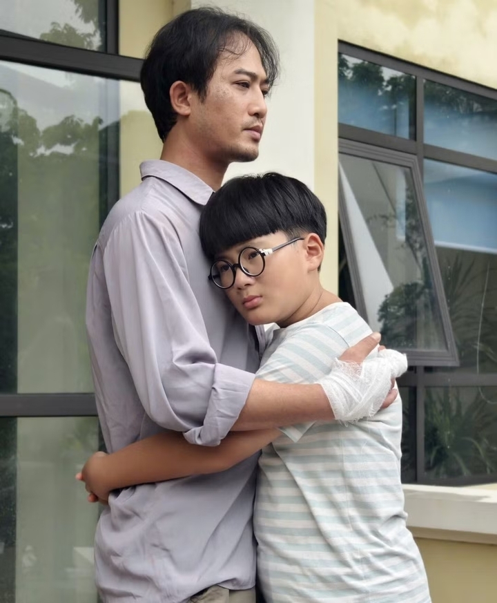 明小在《無頂之家》中飾演康，平（允國潭）和幸（玄Lizzie）的兒子。